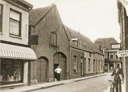 Boliestraat omstreeks 1930. Links de schuur van bakkerij Vinkenborg. Rechts bij het achterste uithangbord zat op nummer 100 Kunst Zoolleder en Schoenfournituren.